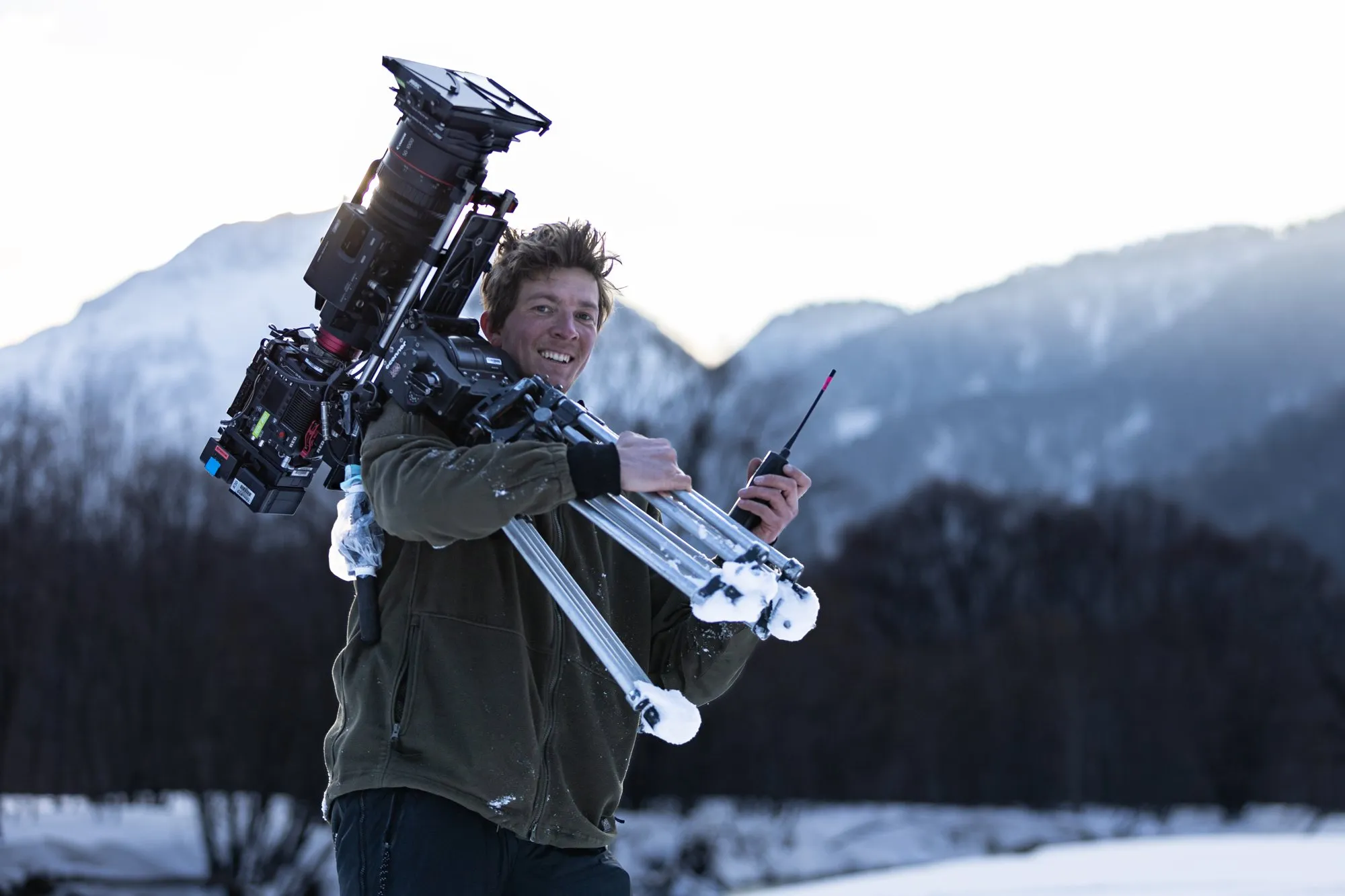 Noah carrying a cinema camera and tripod in the snow